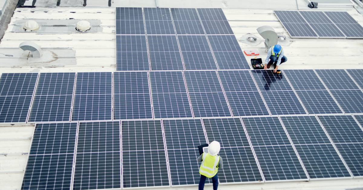 Two solar panels next to energy control boxes. There are four boxes labeled “Energy Storage” mounted onto the wall.