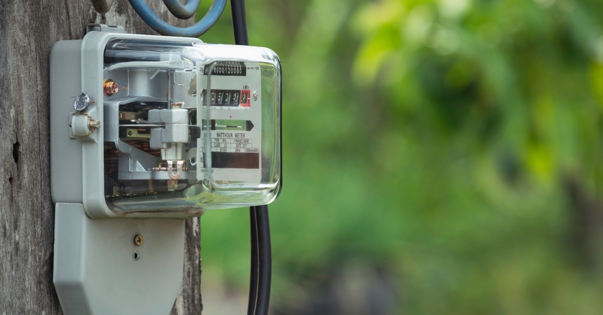 An electric power meter mounted onto a wooden post. There are black and blue wires feeding out of the box.