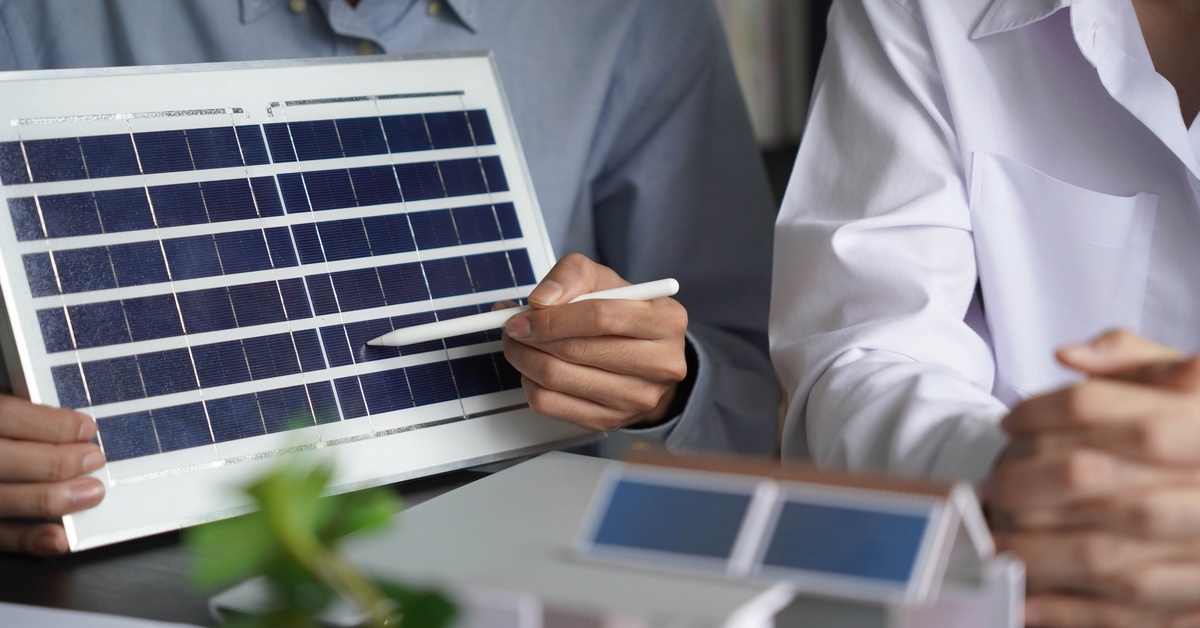 A group of engineers looking at models of solar panels. One of them is holding a model and pointing at a part of it.