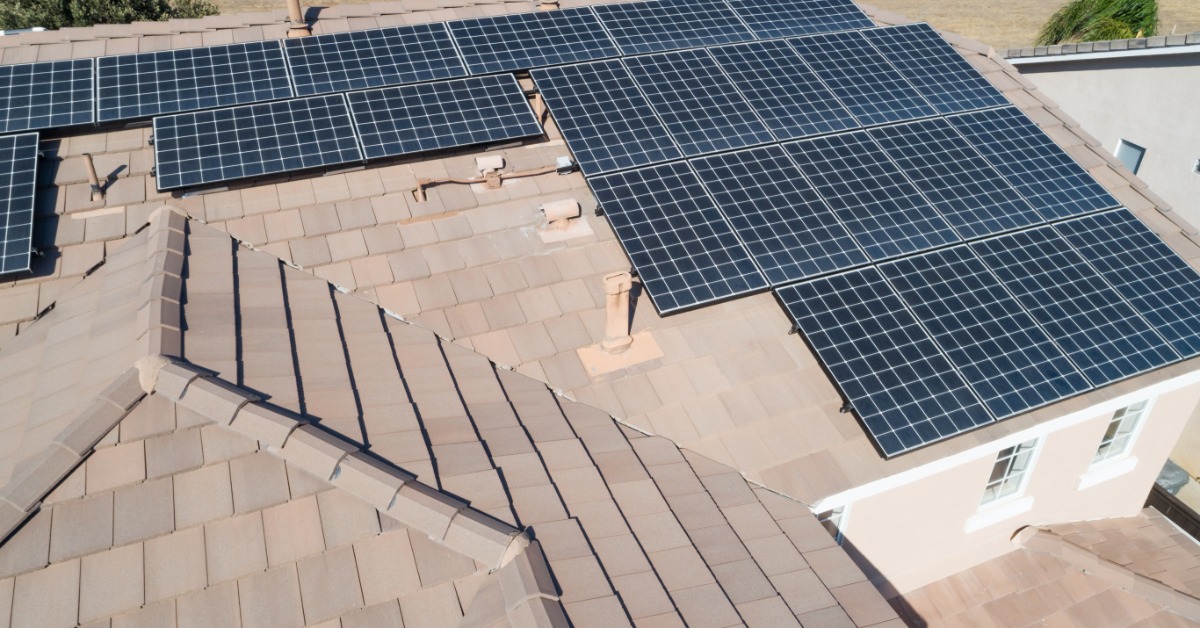A light brown rooftop with solar panels mounted on part of it. The taller areas are free of solar panels.