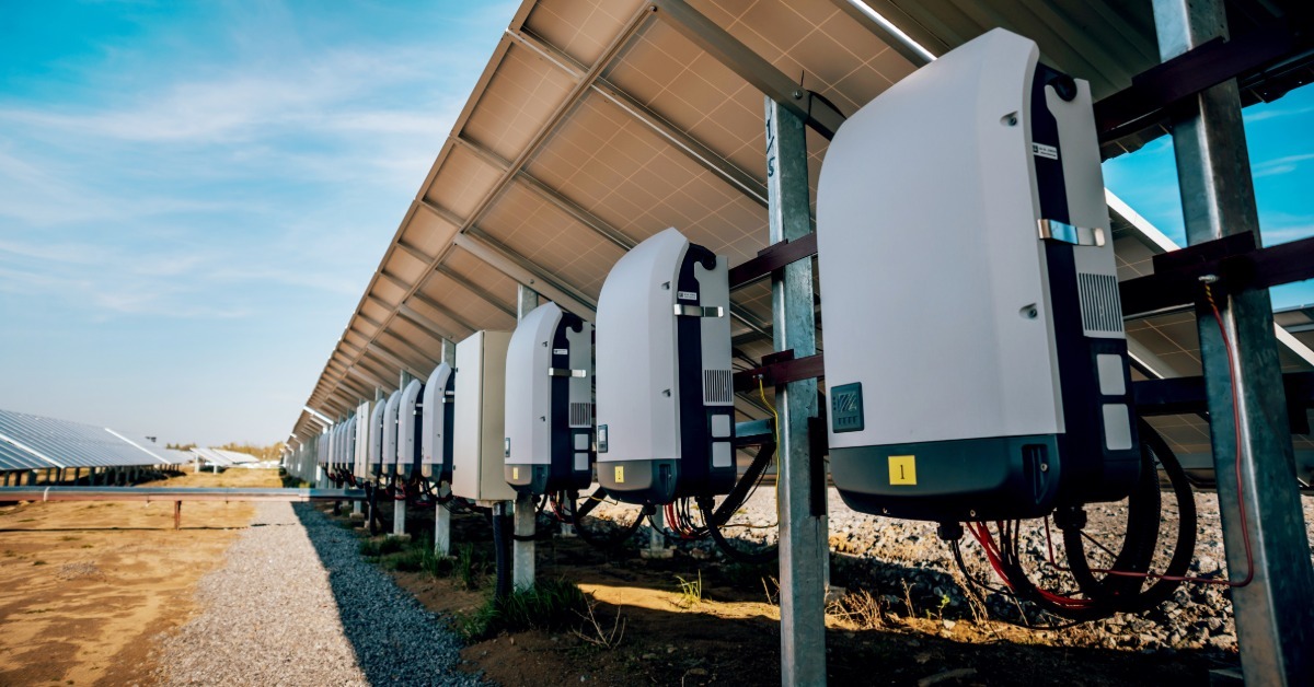 The back of a row of solar panels with other equipment. This includes inverters to transform sunlight into electricity.