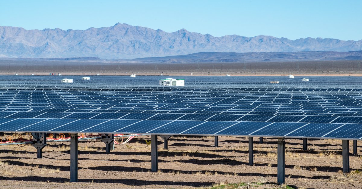 How Engraved Solar Placards Improve Readability Rows of blue solar panels stretching across a flat desert field with dry ground, small buildings, and distant mountains.